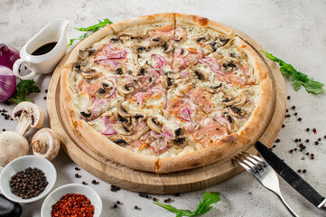 Tasty pizza with ham, mushrooms and onion on the concrete background