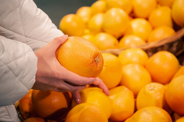 Grapefruit in female hands, buying fruits in a supermarket.