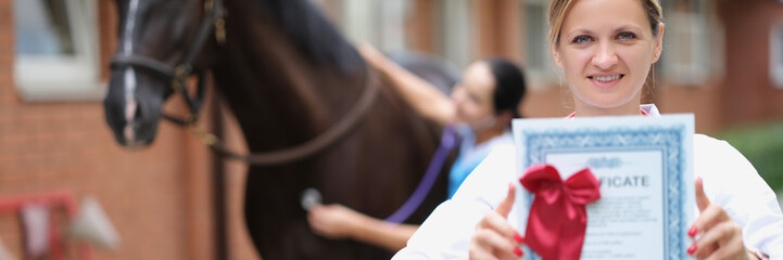 Fototapeta na wymiar Woman veterinarian is holding medical certificate in background horse