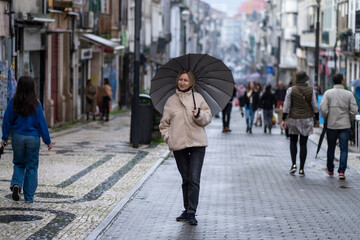 A woman with an umbrella on Santa Catarina main street in Porto, Portugal. .