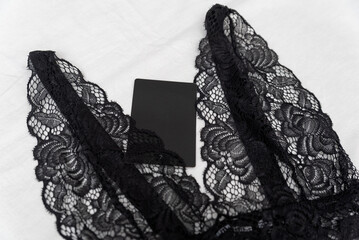 Black lace bralet with empty black tag on white background. Transparent lace sexy lingerie