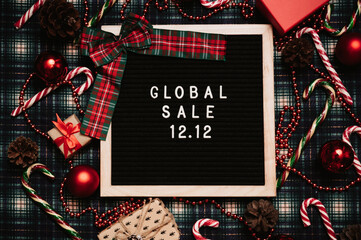 The text of the sale 12.12 on the Christmas decor letter board with a credit card and a mini grocery cart. Design to promote the winter sale at the end of the year. Top view.