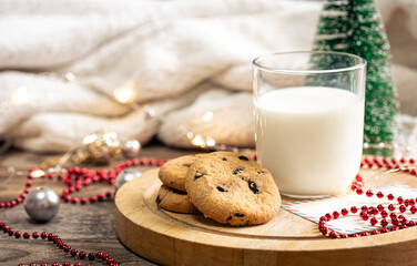 Christmas cookies and glass of milk for Santa on holiday blurred background.