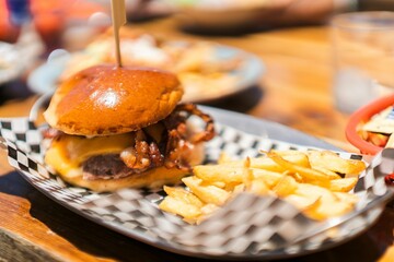 Soft focus of an appetizing burger with cheese and bacon served with fries on the side