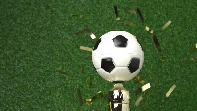 Soccer champion trophy revolves around itself with falling golden confetti. Video 4K