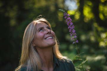 Happy mature woman with blond hair standing in garden