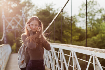 Teenage girl using smartphone and listening music on a bridge