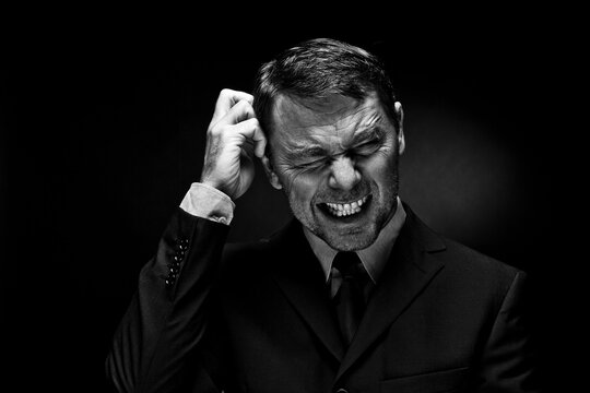 Mature man clenching teeth against black background