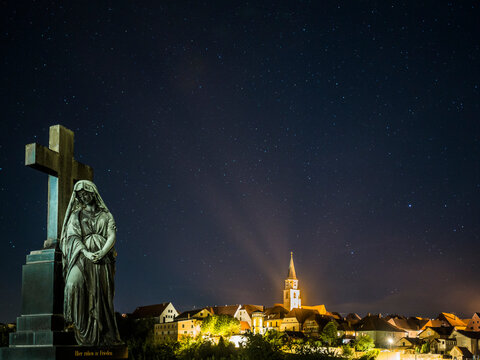 Germany, Bavaria, Nabburg, Tombstone at night with illuminated town in background