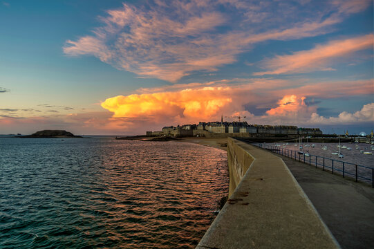 Pier towards old town in St. Malo amidst sea at sunset