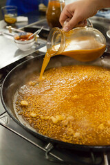 Paella gourmet elaboration stills. A big rice and spices boiling on a paellera while a chef moving...