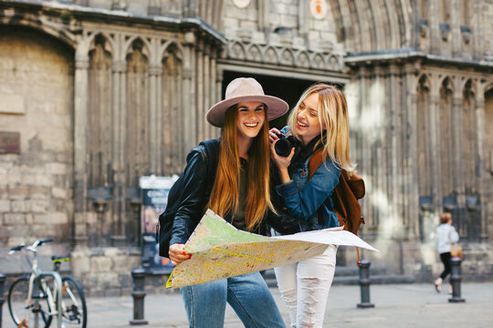 Spain, Barcelona, two happy young women with camera and map