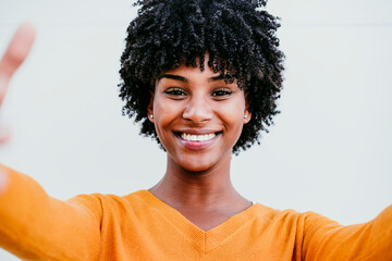 Smiling woman with Afro hair taking selfie