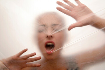 Young woman screaming behind foil