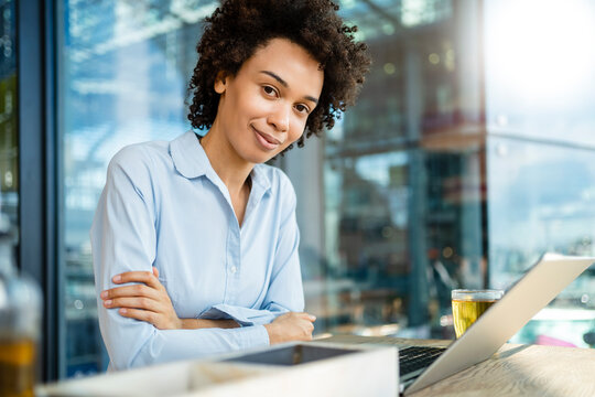 Smiling businesswoman with arms crossed by laptop at office