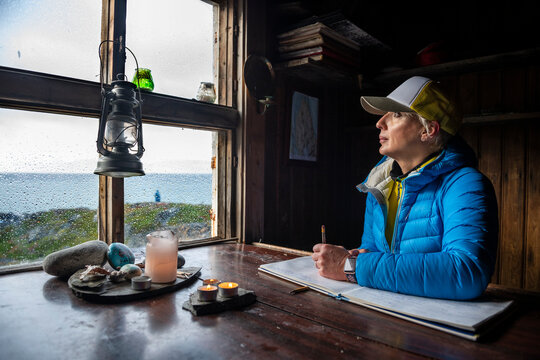 Thoughtful mature woman sitting in log cabin