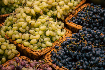 Baskets with different types of grapes on a supermarket showcase.