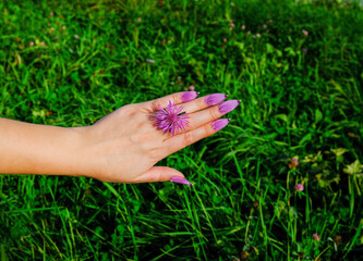 female hand with false nails made of flower petals