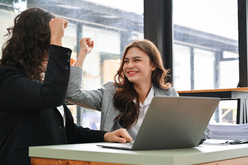 Attractive Caucasian businesswoman smiling and celebrating with her colleague