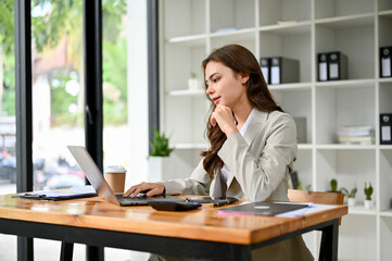Attractive young caucasian businesswoman working on her project on laptop