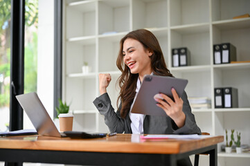 Happy and overjoyed young caucasian businesswoman looking at laptop screen