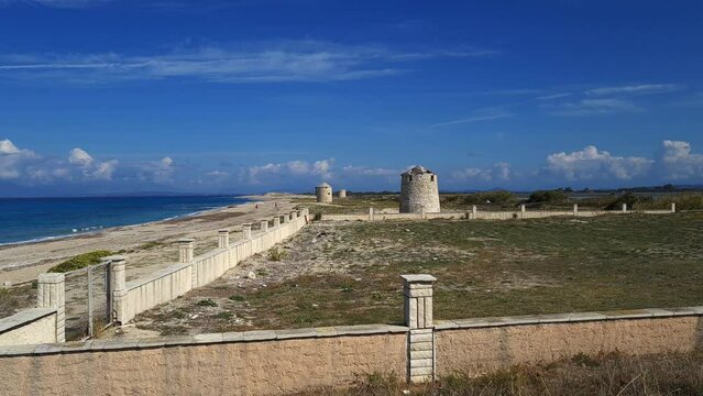 A beautiful long sandy beach with derelict stone wind mills on a sunny day.
