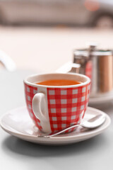 Morning red cup with fresh black tea on urban cafe terrace
