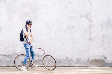 Fototapeta premium Portrait of casual hipster handsome businessman with backpack talk on smartphone while commuting riding bicycle on the street city way go to work.business travel transport bike concept