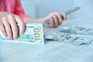 Woman counting dollars at table.