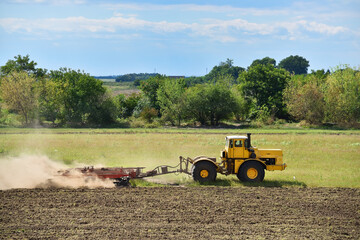 Yellow tractor on land cultivating. Agricultural tractor on cultivation field.