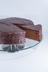 sacher torte chocolate Viena brown portion slice white background, cristal plate