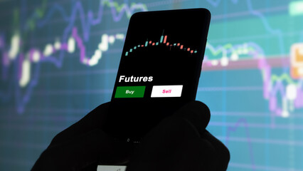 An investor's analyzing the futures etf fund on screen. A phone shows the ETF's prices futures to invest