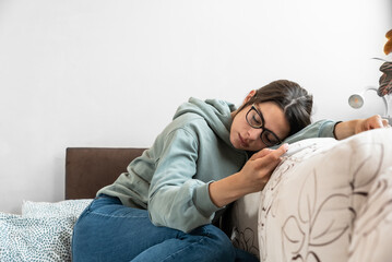Fototapeta premium Young frustrated sick woman ill from common cold and flu virus measuring her body temperature, feeling miserable and weak. Business woman cant go to the work due to sickness.