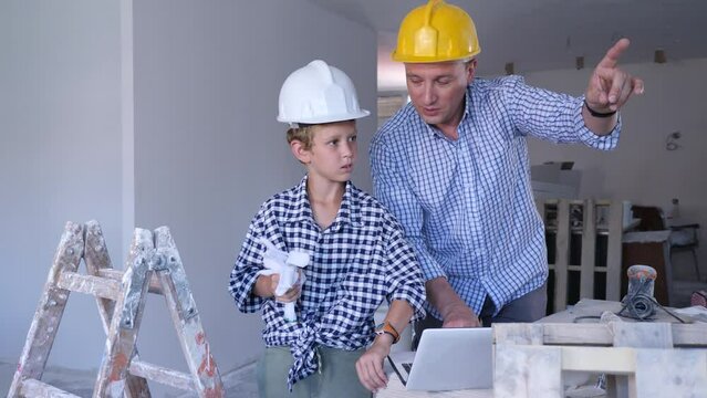 Portrait of man architect and boy using laptop while discussing working process in house being renovated. High quality 4k footage