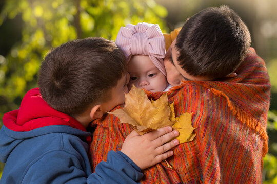 Two Brothers - Older And Younger, In The Autumn Park, Hold Their Sister - A Baby, Kissing Her, Close-up