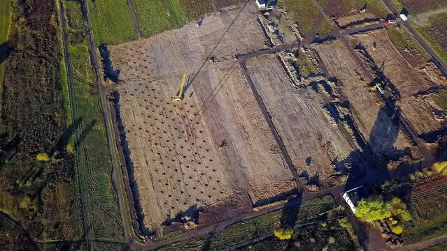Aerial drone high angle shot of compaction machine and trucks for earth compaction busy doing ground works going on a sunny day.