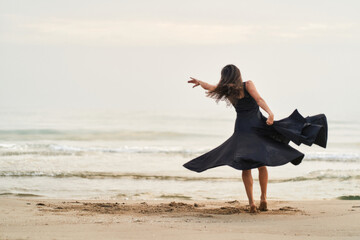 a dancer in a black dress on the beach expressing strength and courage in her movements