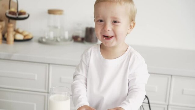 A Happy Child Is Eating. Attractive Boy In The Kitchen Eating Cookies With Raisins, Oatmeal Cookies With Pleasure. The Child Is Smiling And Happy