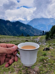 Obraz premium A selective focus on Tea Cup at Blur Top Mountain View of Kalam Valley in Clouds 