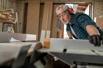 Fototapeta na wymiar Carpenter in ear protectors working in a workshop