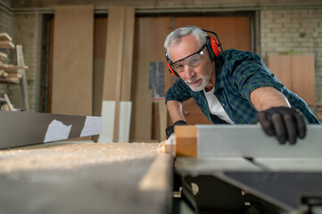 Carpenter in ear protectors working in a workshop