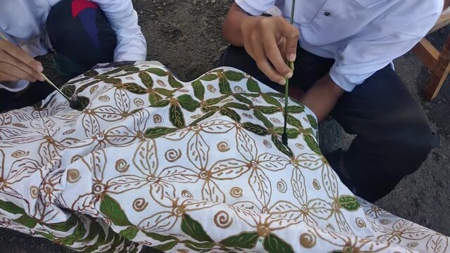 close-up of hands sticking eco friendly batik motifs. heritage asian fashion.