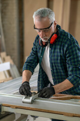 Craft man in plaid shirt working in a carpenter workshop