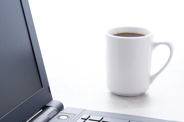 コーヒーを飲みながらノートパソコン（黒）でデスクワーク