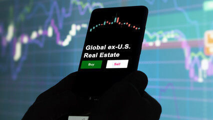 An investor's analyzing the Global ex-U.S. Real Estate etf fund on screen. A phone shows the ETF's...