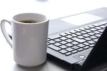 コーヒーを飲みながらノートパソコン（黒）でデスクワーク
