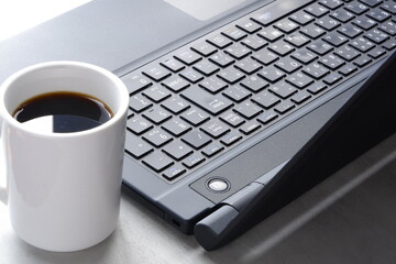 Obraz na płótnie Canvas コーヒーを飲みながらノートパソコン（黒）でデスクワーク