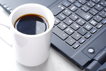 コーヒーを飲みながらノートパソコン（黒）でデスクワーク