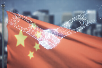 Abstract virtual blockchain technology hologram with handshake on flag of China and blurry skyscrapers background. Digital money transfers and decentralization concept. Multiexposure