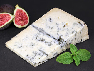 delicious italian gorgonzola with mint leaves and figs on black slate board, tasty piece of original blue cheese